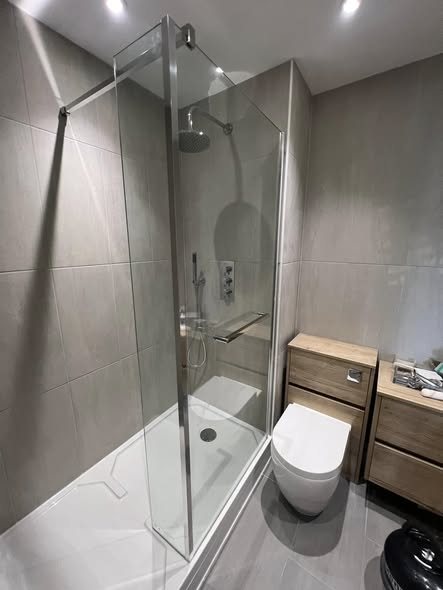 Walk-in shower room with grey tiles, a wall-hung toilet and an oak vanity unit