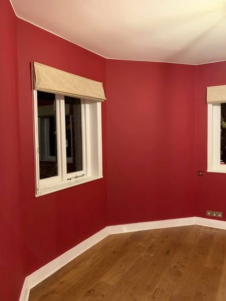 Bedroom painted deep red with white woodwork and an oak floor