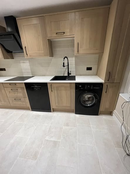 Oak shaker kitchen sink run with a black tap and black extractor hood